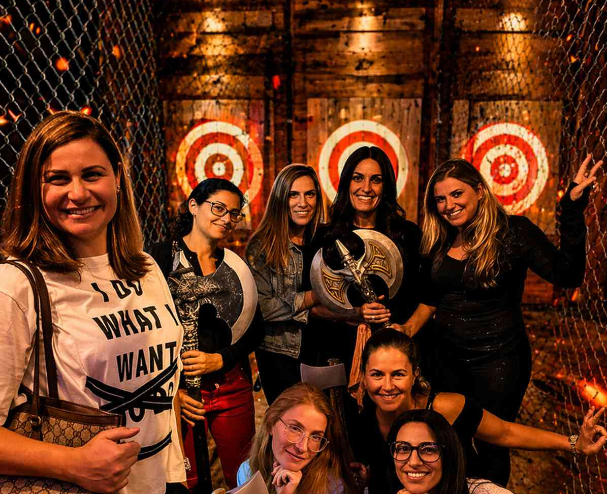 Group of women smiling and holding axes at an indoor axe throwing venue in Hollywood Florida