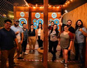 Group of friends enjoying axe throwing together at Extreme Axe Throwing in Hollywood Florida, posing in front of colorful targets