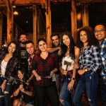 Large group of friends smiling and holding axes at an indoor axe throwing venue in Hollywood Florida