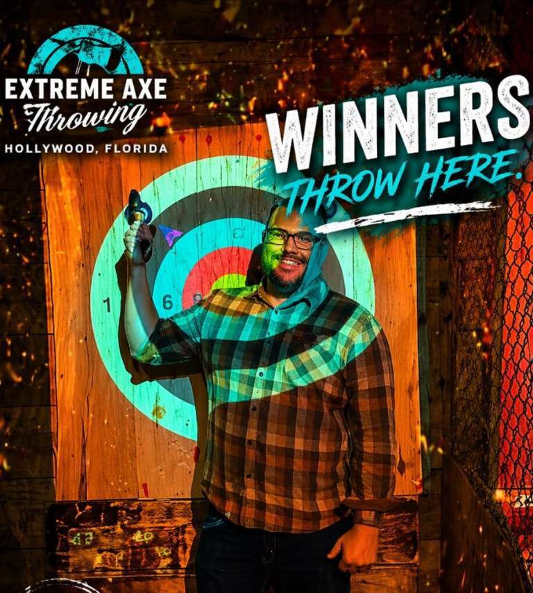 Man holding axe and smiling after a successful throw at Extreme Axe Throwing Hollywood Florida