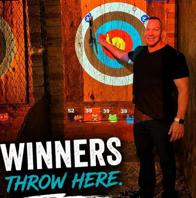 Man pointing at bullseye after successful axe throw at Extreme Axe Throwing Hollywood Florida