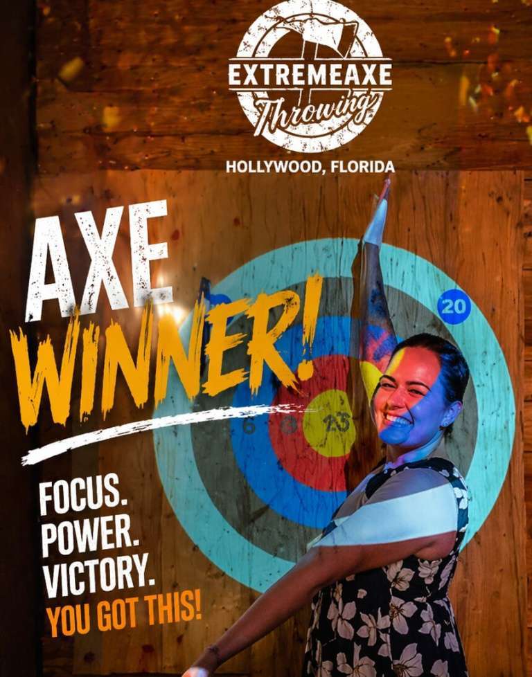 Woman celebrating a successful axe throw in front of a lit target at Extreme Axe Throwing Hollywood, Florida