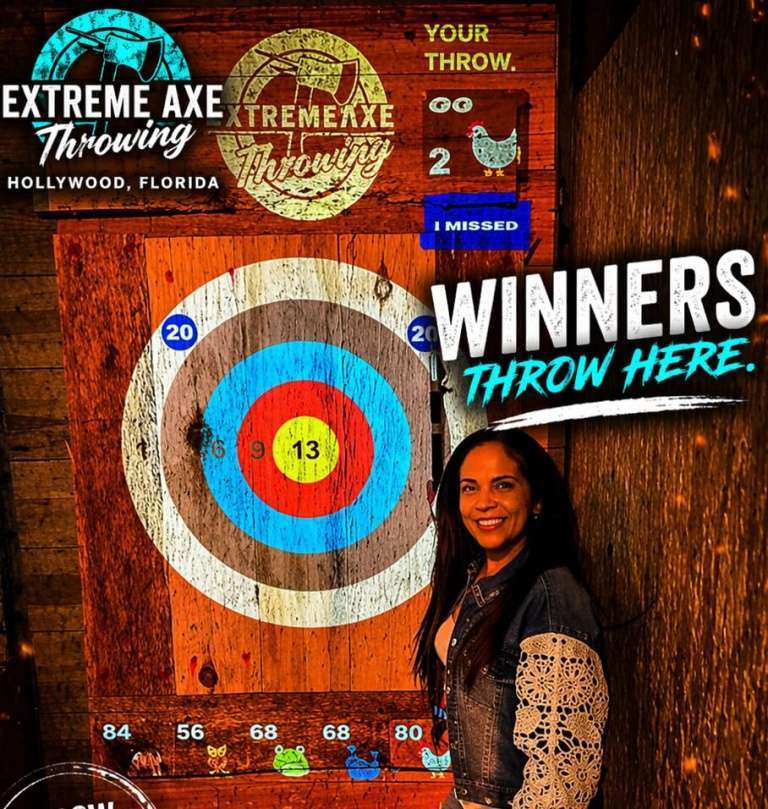 Woman smiling next to axe in target at Extreme Axe Throwing Hollywood Florida winner moment