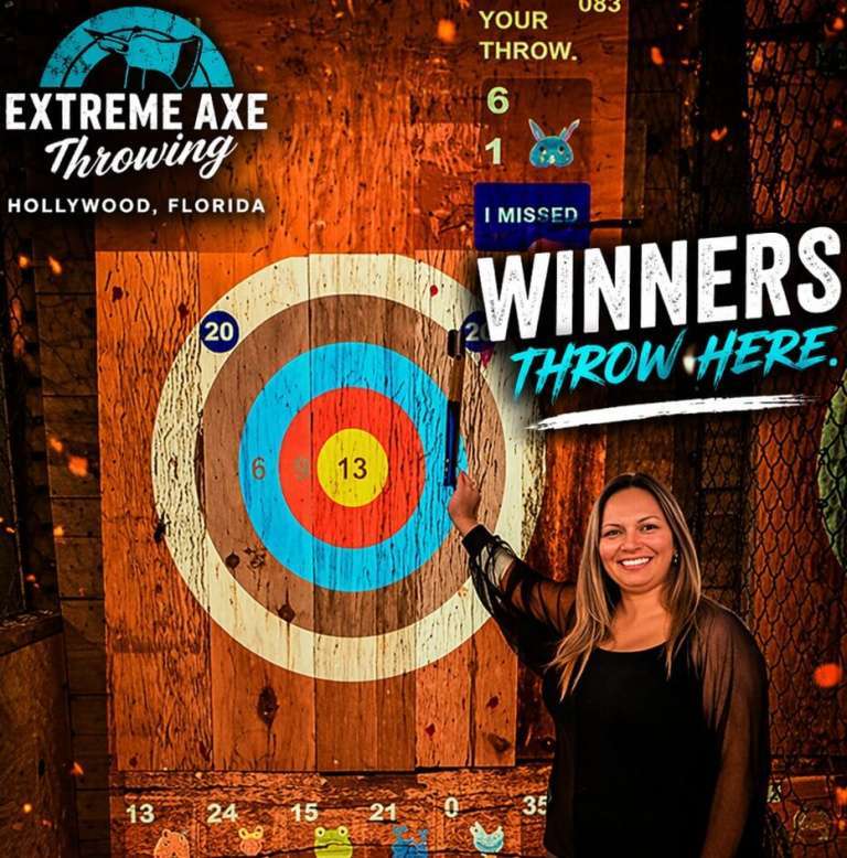 Woman pointing at axe in target after successful throw at Extreme Axe Throwing Hollywood Florida