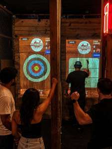 Adults enjoying indoor axe throwing nightlife activity at Extreme Axe Throwing Hollywood in Florida